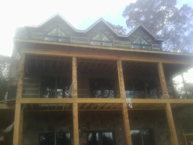 Dormers and porch framing on a large log home under construction — Roof Coating work by our crew in Jonesburg