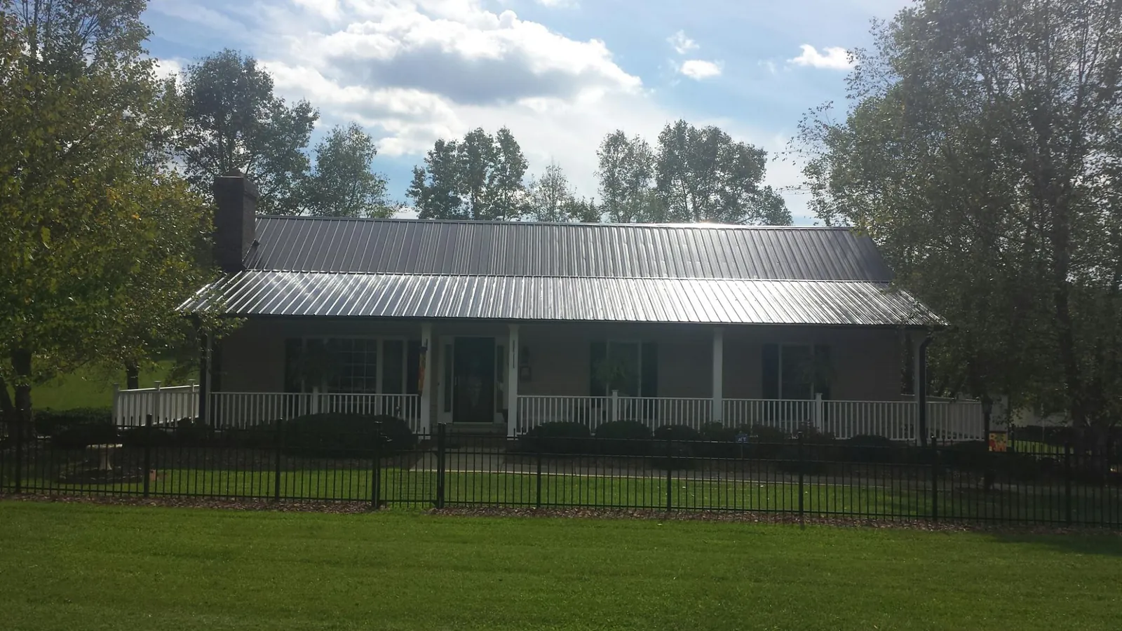 Gray metal roof on a brick ranch with a full width front porch — Gutter Guard Installation work by our crew in Jonesburg