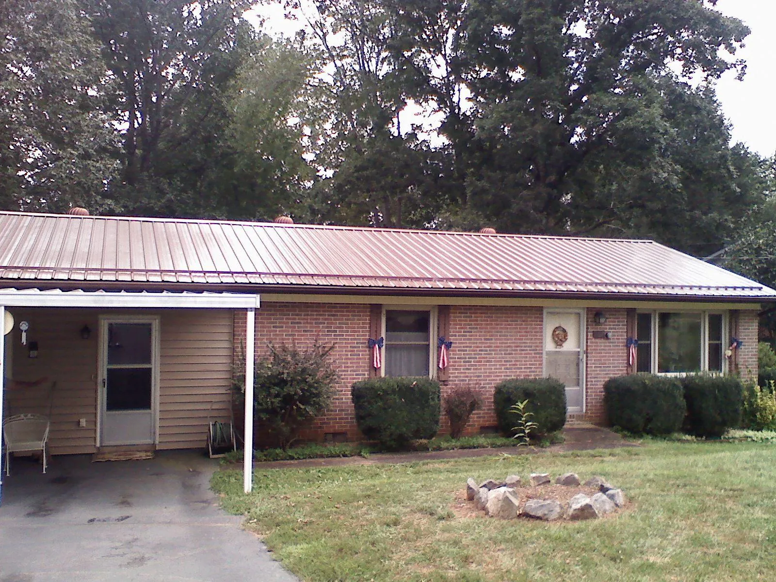 Bronze metal roof and carport on a brick ranch home — Roof Repair work by our crew in Jonesburg
