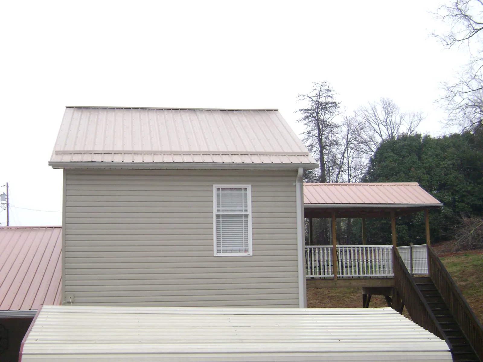 Tan metal roofs on a two story addition and attached porch, from a Roof Replacement job in Jonesburg