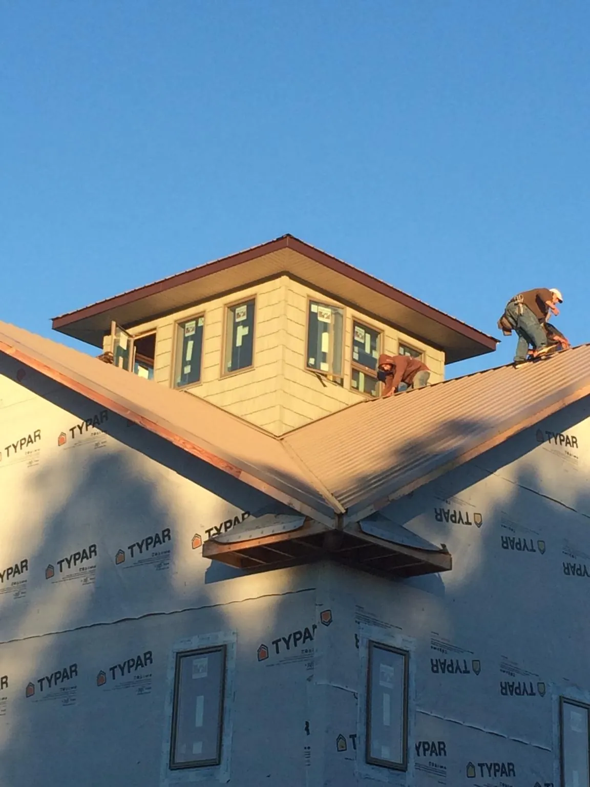 Roofers working around a rooftop cupola on a new metal roof at sunset — Roof Waterproofing in Jonesburg by Roofing Brothers